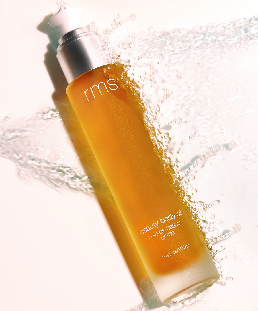 Glass bottle of RMS Beauty Body Oil with a pump dispenser, showing a lightweight, golden-hued oil designed to hydrate and nourish the skin
